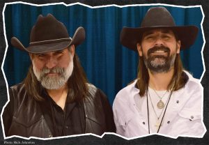 Profile picture of the Fillbach Brothers pictured from the chest up. They both have shoulder length long dark hair and black cowboy hats. Both of them have full beards.